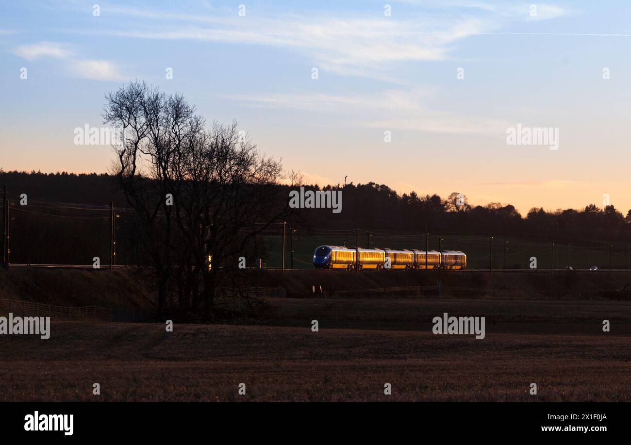 Open access operator Firstgroup Lumo class 803 electric train on the 4 track east coast mainline railway in Scotland glinting at sunset Stock Photo