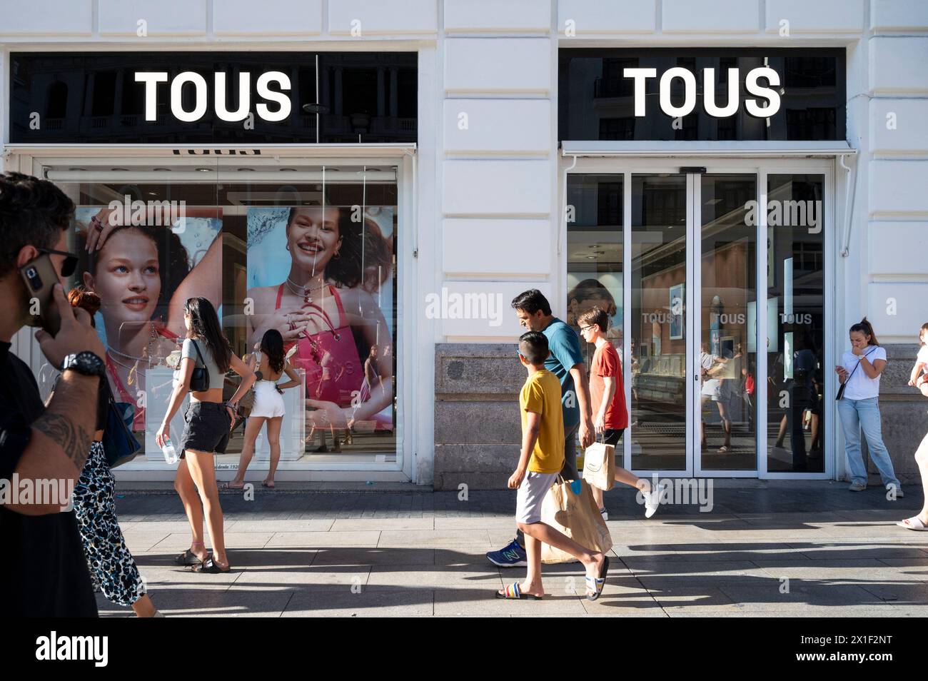 Pedestrians and shoppers walk past the Spanish jewelry, accessories, and fashion retailer Tous store in Spain. Stock Photo