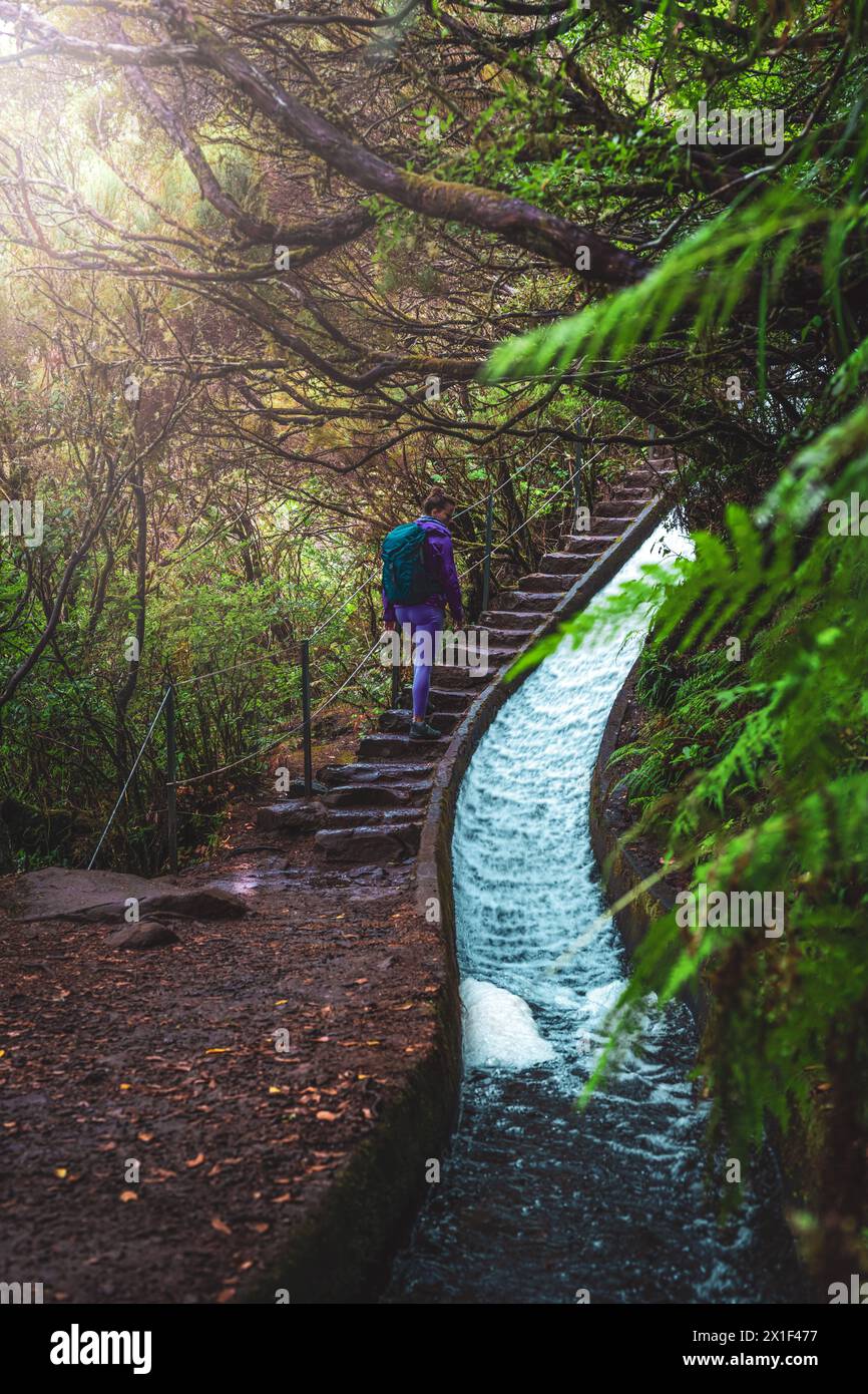 Description Female tourist with backpack walks up a stair path next to a sloping water channel