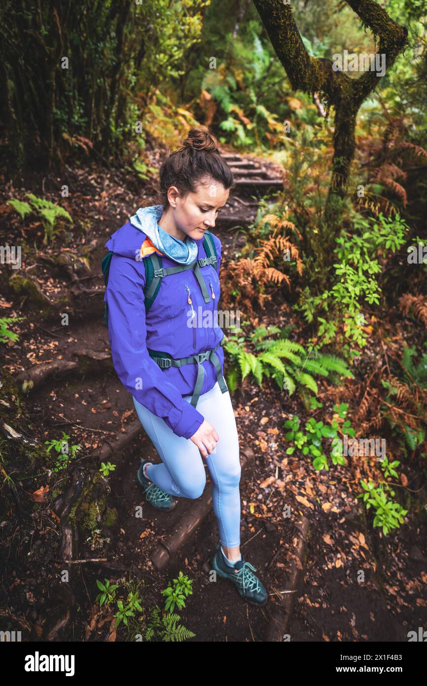Description: High angle shot of female tourist with backpack hiking down a stary path through a picturesque deciduous forest. 25 Fontes waterfalls, Ma Stock Photo