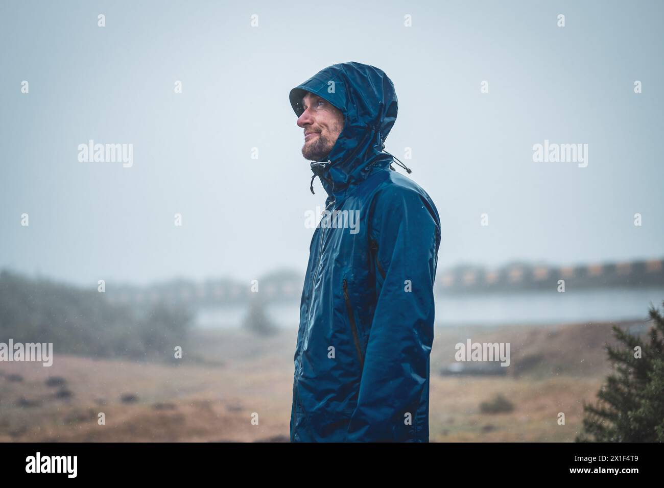 Description: Disillusioned and healthy male tourist with hands in trouser pockets looking at rainy sky with questioning facial expression. 25 Fontes W Stock Photo