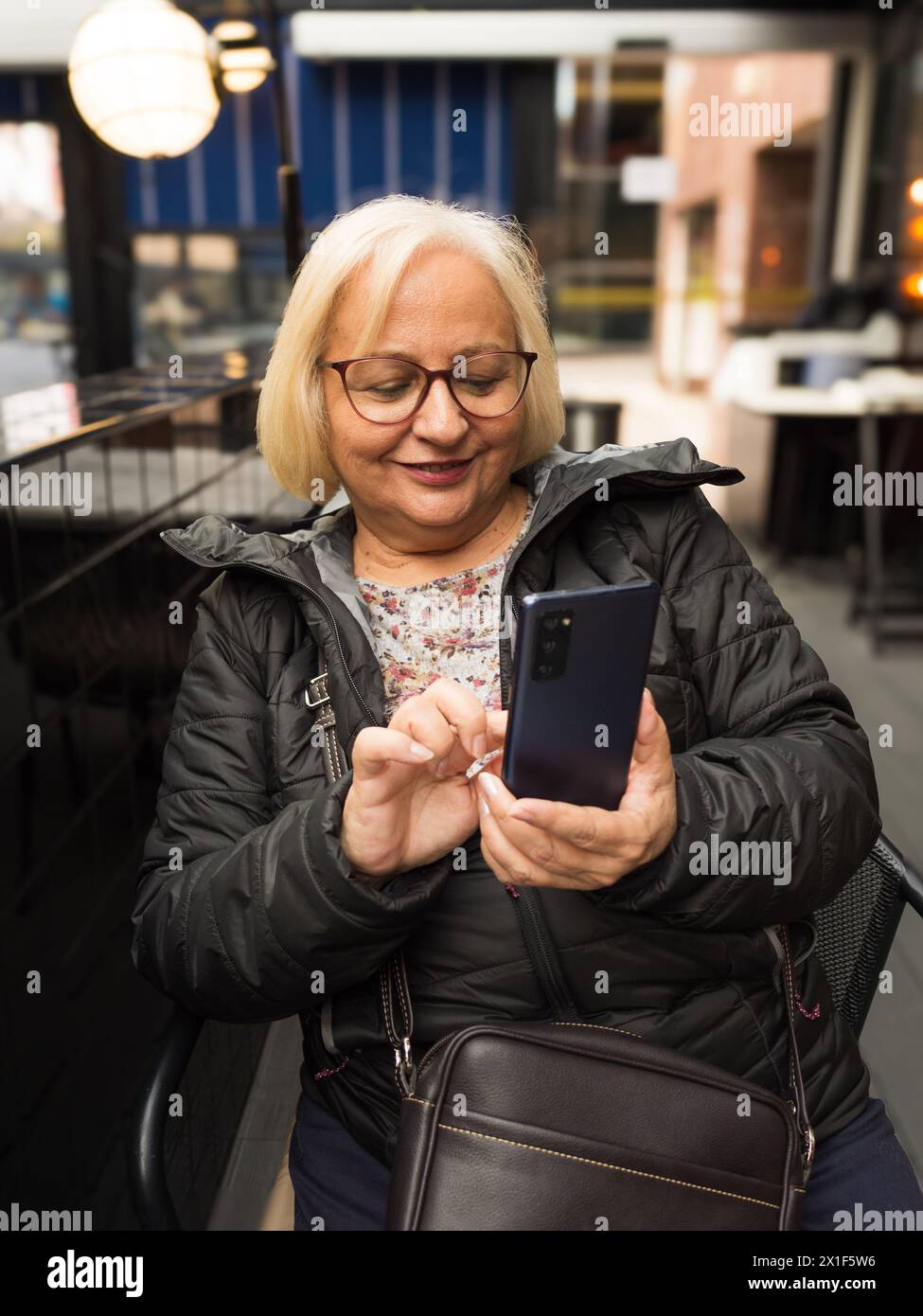 happy blonde senior woman touching cell phone Stock Photo