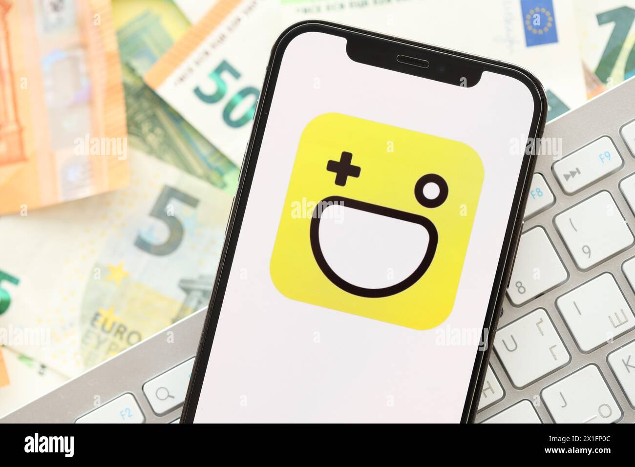 KYIV, UKRAINE - APRIL 1, 2024 Hago icon on smartphone screen on many euro money bills. iPhone display with app logo with european currency euro banknotes and white keyboard Stock Photo
