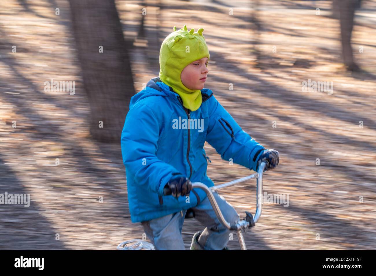 Yellow And Blue Rides Seven years old little boy rides a bicycle in the autumn park. A boy in ...