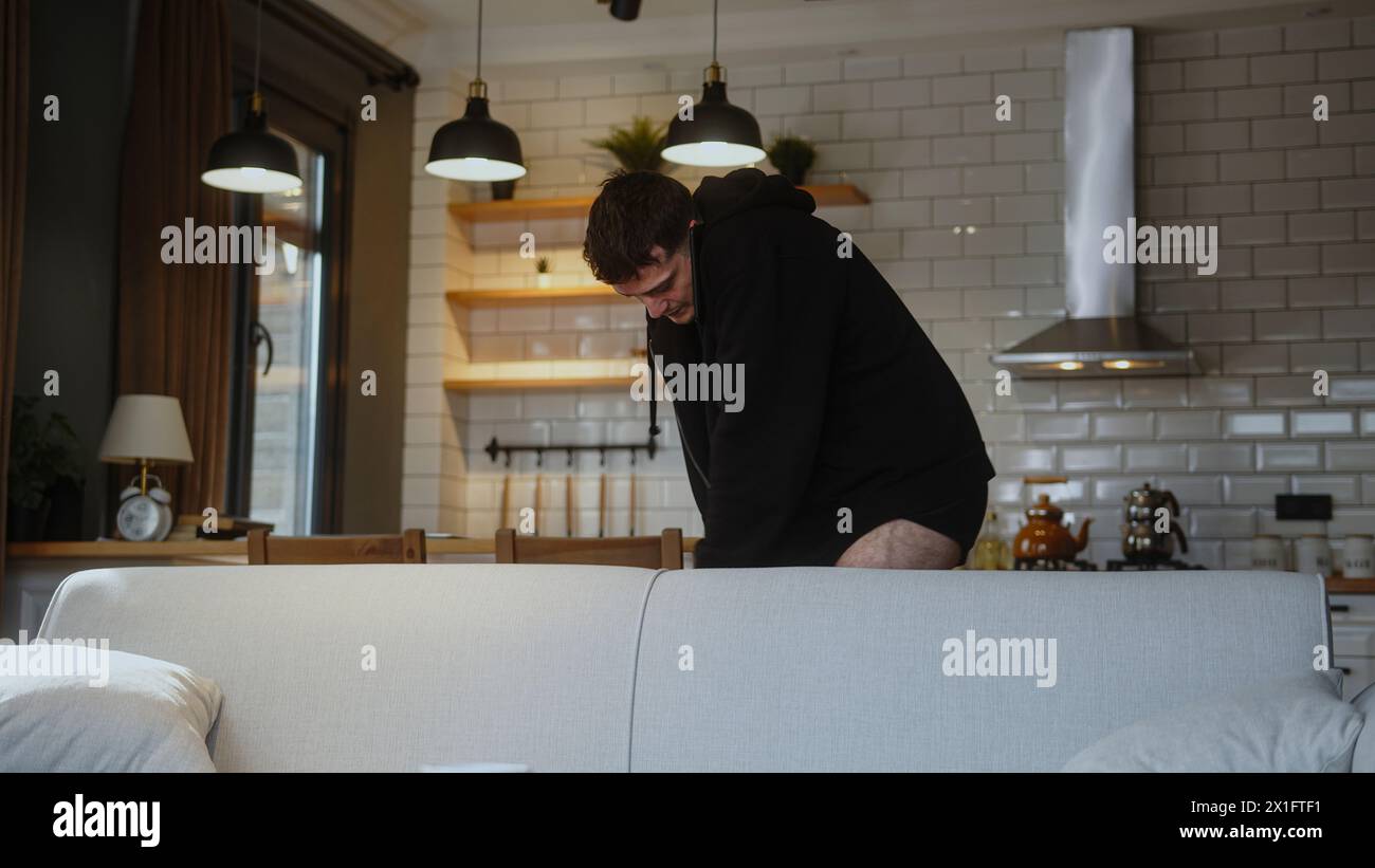 Young man in a hurry to go to work, wearing jeans and talking on the phone, hurriedly gets ready for work. Stock Photo