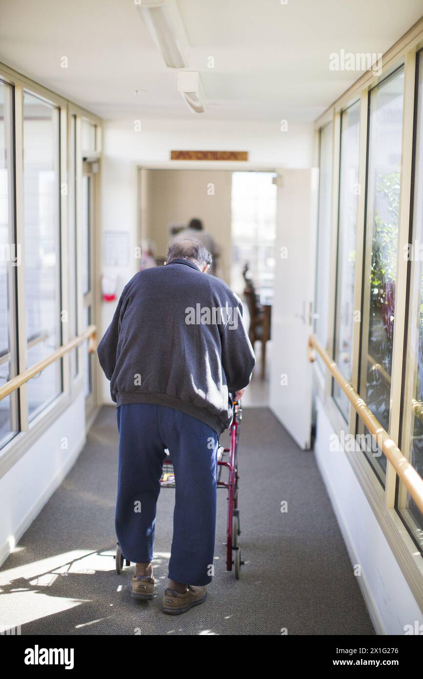 ELDERLY MAN WALKING DOWN CORRIDOR USING MOBILITY WALKER FOR SUPPORT ...