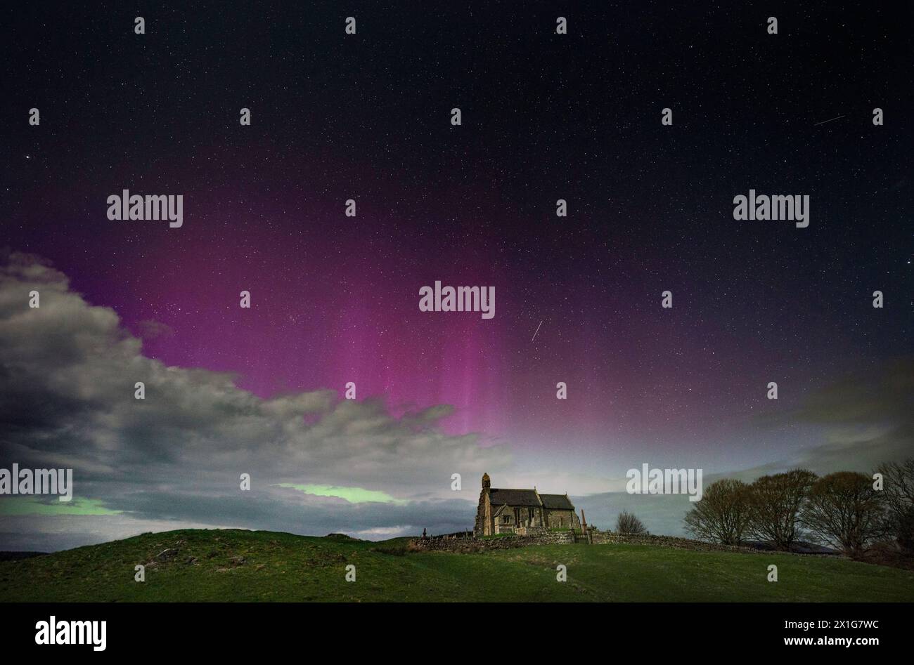 The aurora borealis, also known as the Northern Lights, illuminate the sky just before midnight over St Aidan's church in Thockrington, Northumberland. Picture date: Wednesday April 17, 2024. Stock Photo