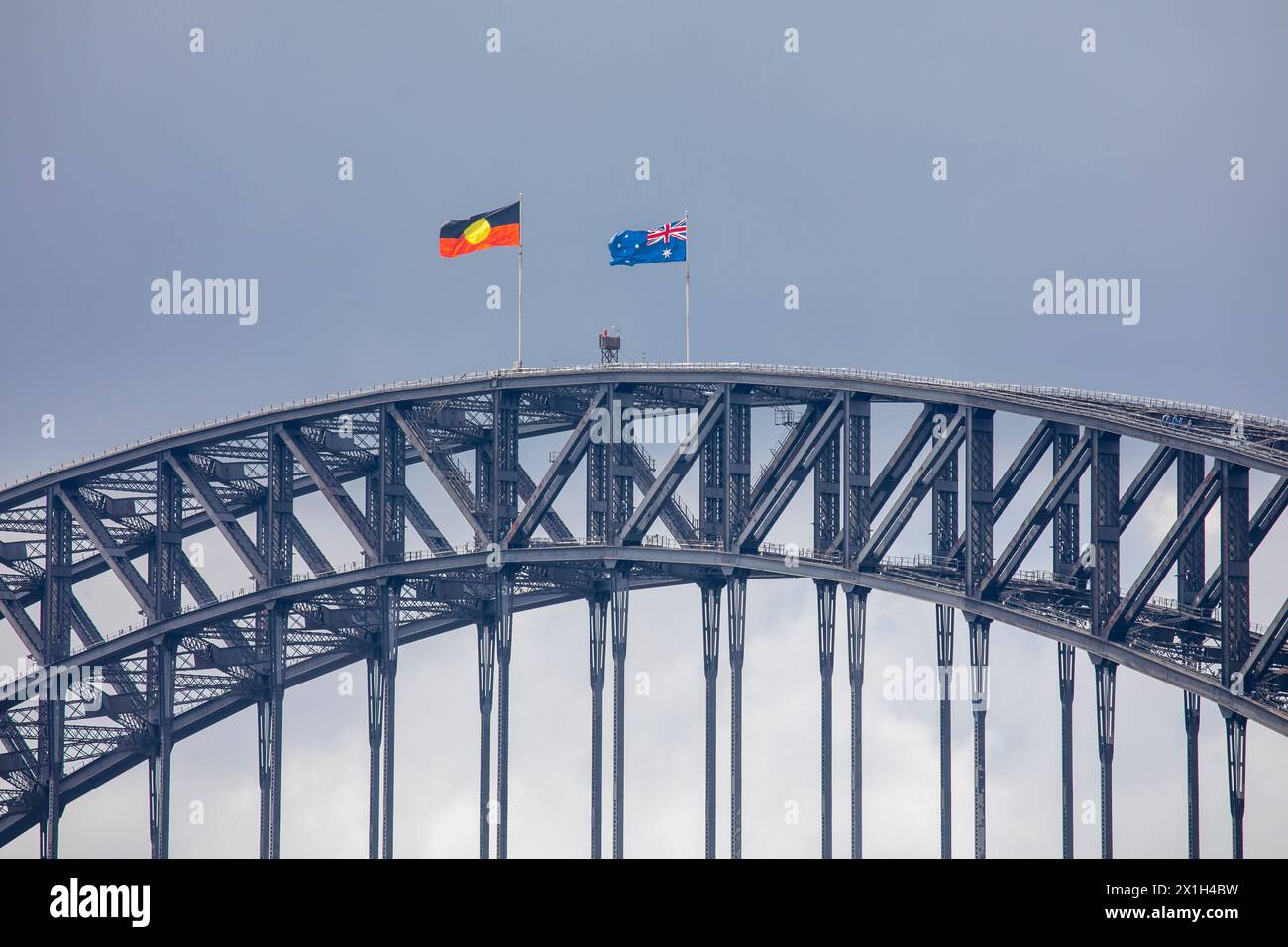 Opened in 1932, the iconic Sydney harbour Bridge flies the australian national flag and the aboriginal indigenous flag Stock Photo