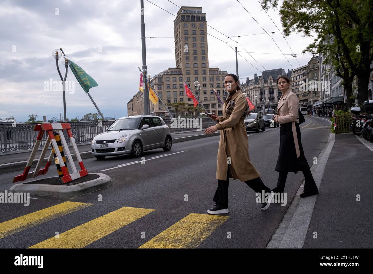 Two young women in luxurious clothes crossing the road with the Bel-Air tower in the background in Lausanne, Switzerland on 19 May 2023. Lausanne is a Stock Photo