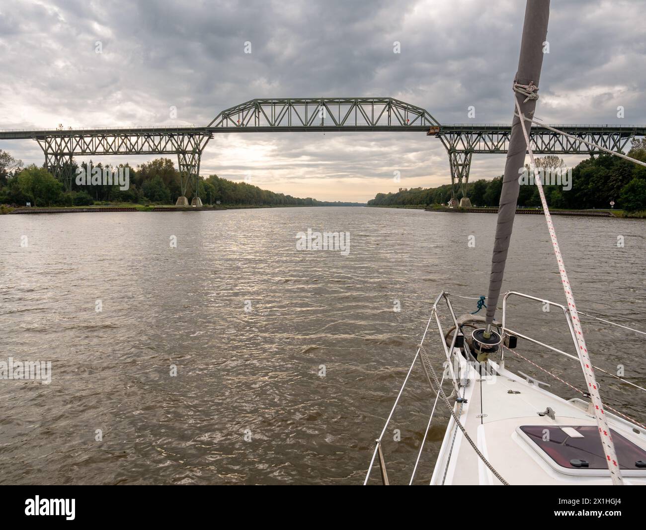 Sailboat approaching Hochdonn High Railway Bridge on Kiel Canal, Schleswig-Holstein, Germany Stock Photo