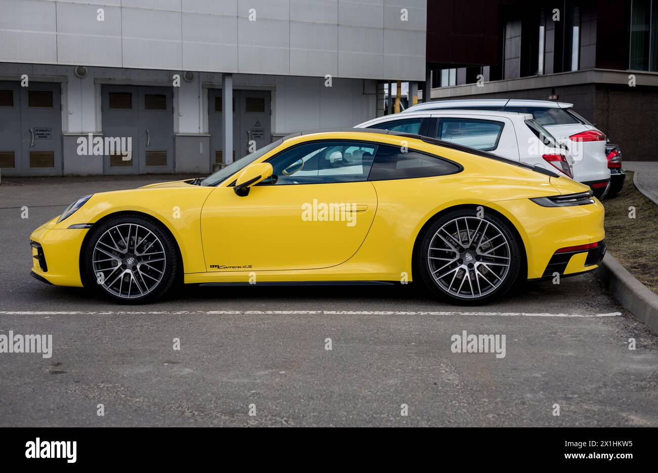 Minsk, Belarus, April 17, 2024 - Side vie luxury coupe yellow Porsche 911 Carrera 4s parking in street Stock Photo