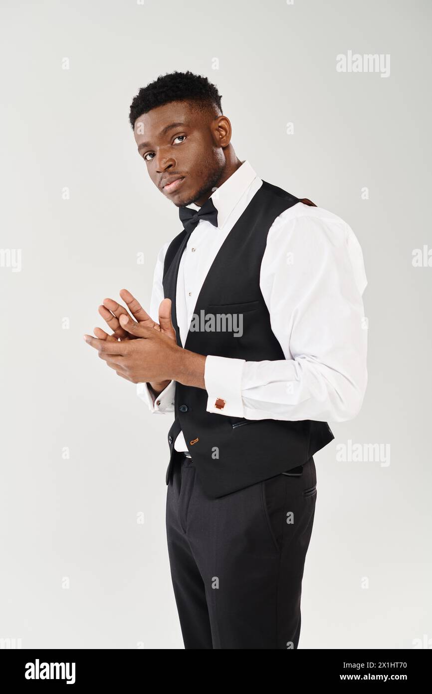 A stylish young African American man stands confidently in a black vest ...
