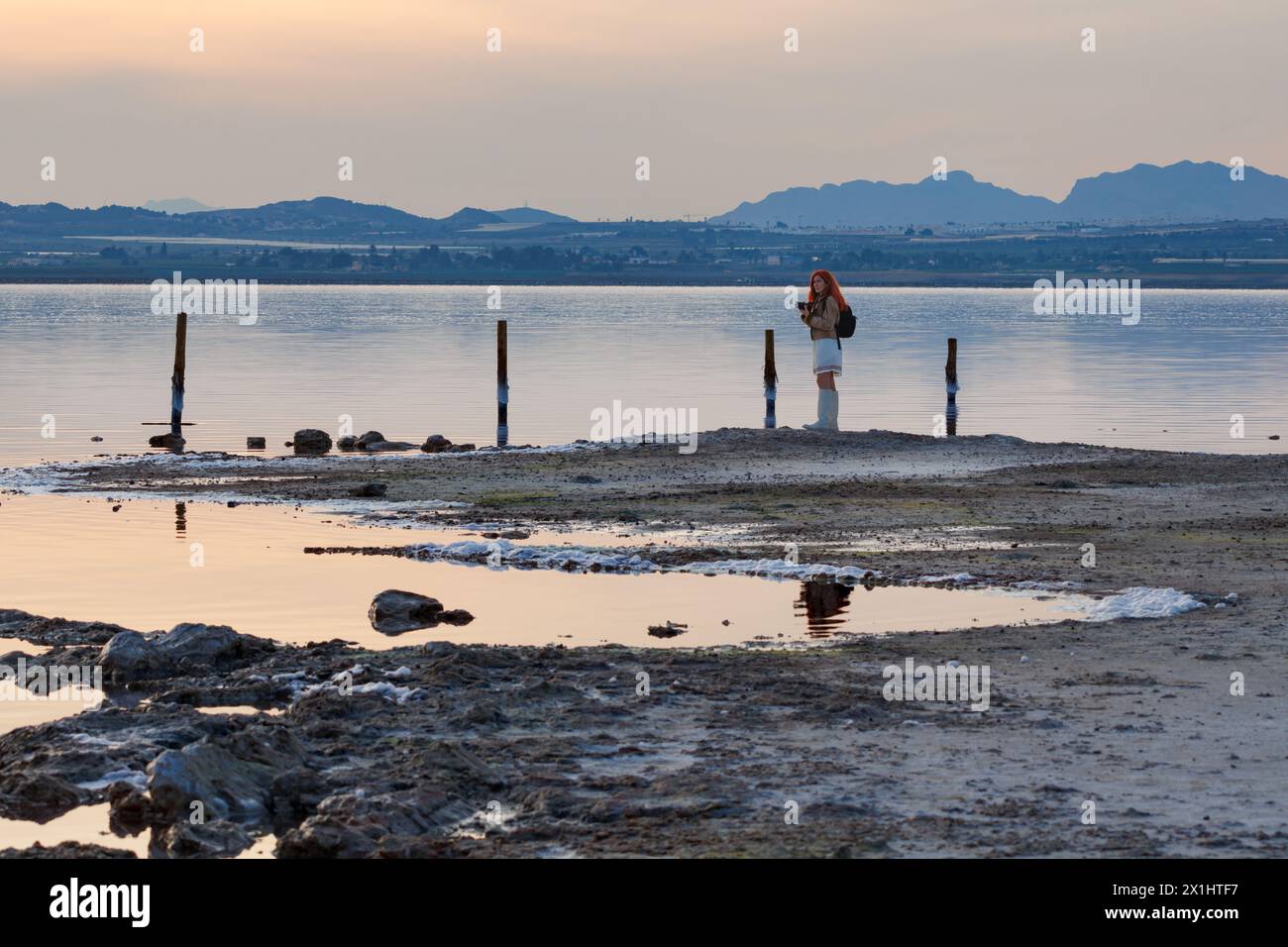 Woman photographing the sunset in the salt flats of Torrevieja, Spain Stock Photo