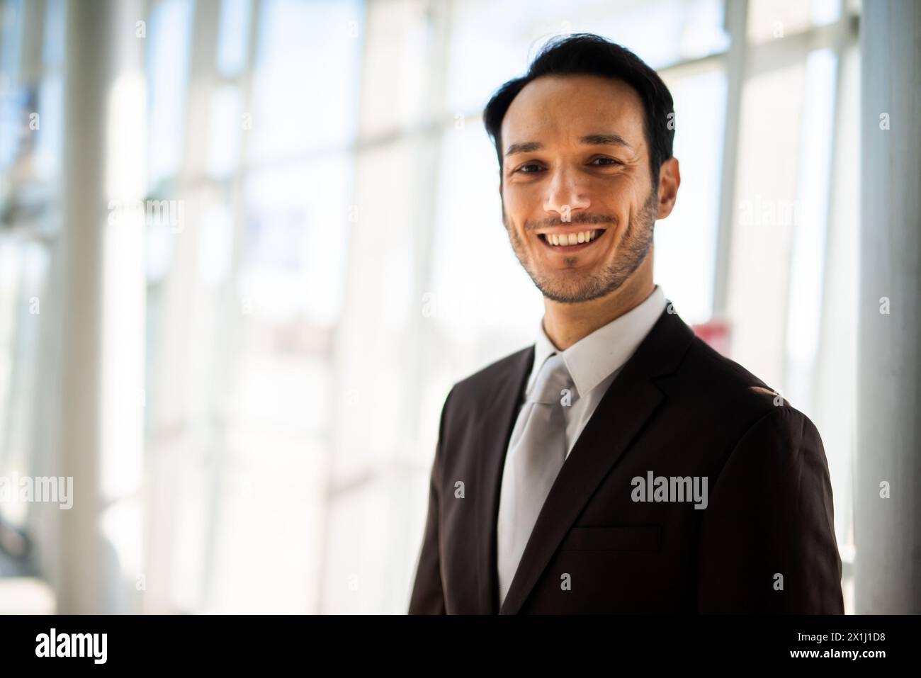 Portrait of a cheerful young businessman in a suit indoors with natural light Stock Photo