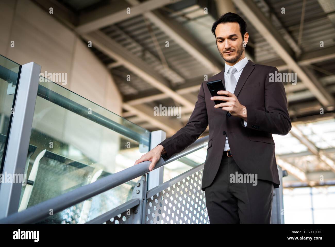 Young professional man using mobile phone while waiting at a modern train station platform Stock Photo