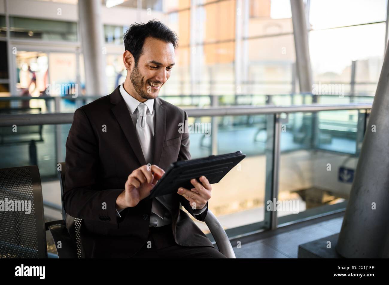 Dapper businessman engages with digital tablet while waiting for his flight at an airport terminal Stock Photo
