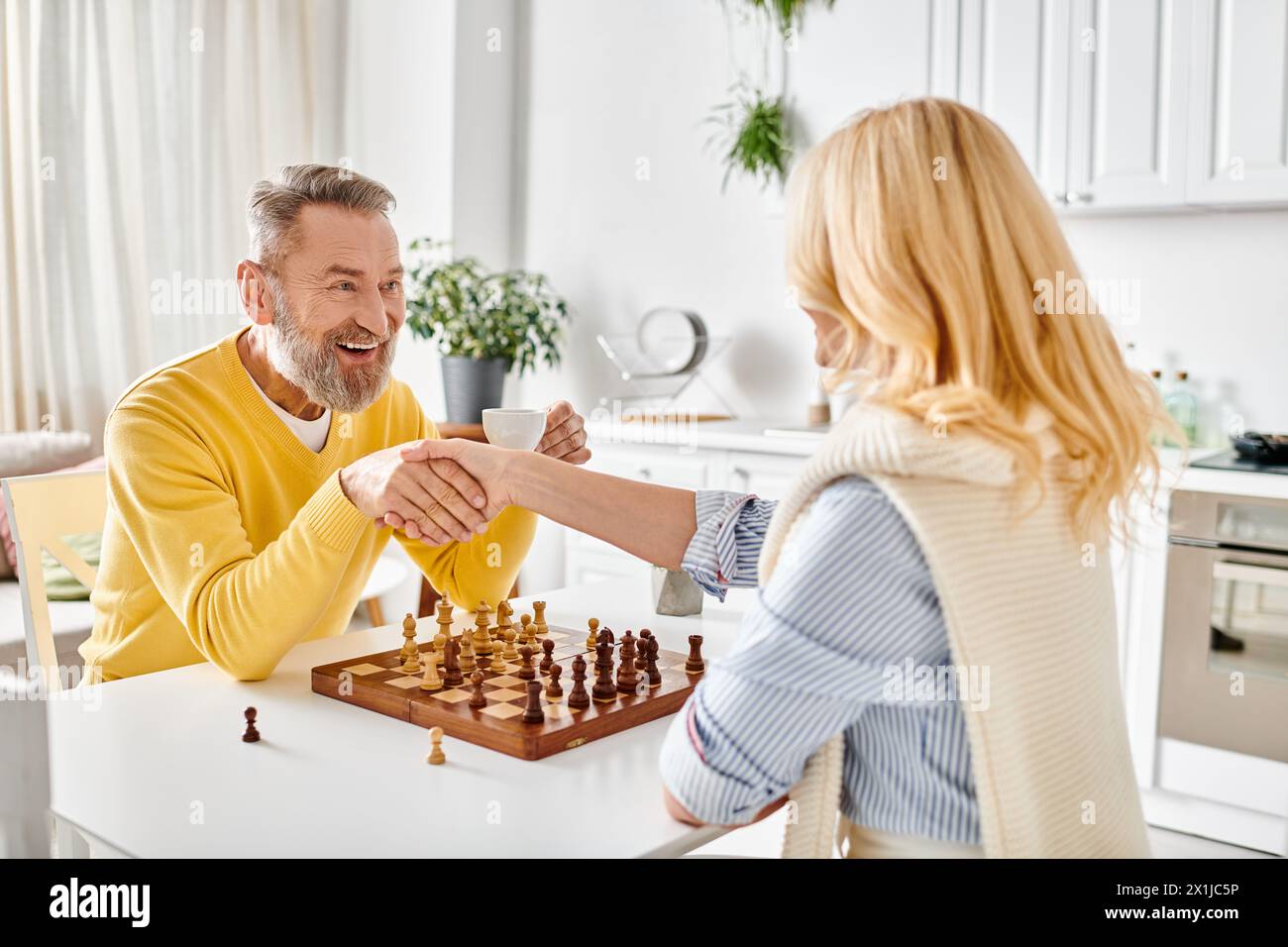 A mature man and woman engaged in a strategic game of chess in their ...