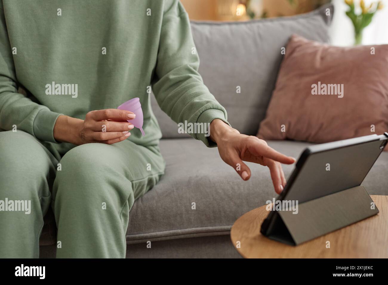 Close up of unrecognizable woman using digital tablet and holding menstrual cup while researching womens health advice online copy space Stock Photo