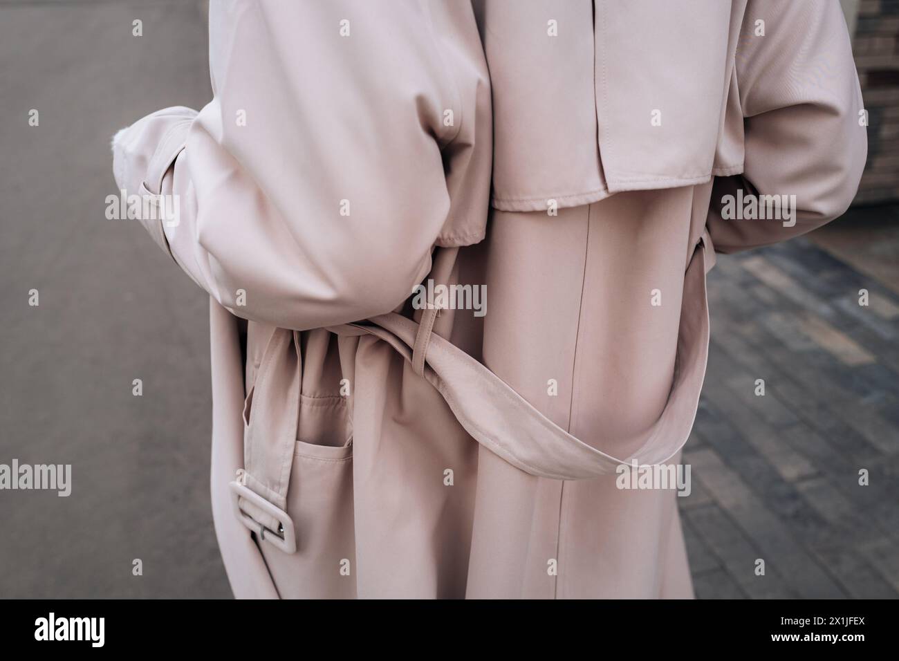 Street style fancy details of a beige women's trench coat with belt. Back view. Contemporary urban fashion cloth Stock Photo