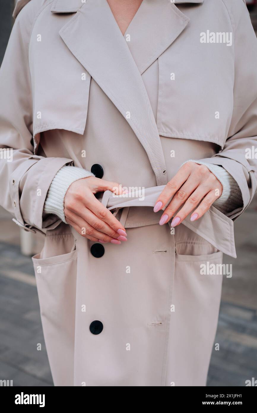 Street style fancy details of a beige women's trench coat with belt. Contemporary urban fashion cloth Stock Photo