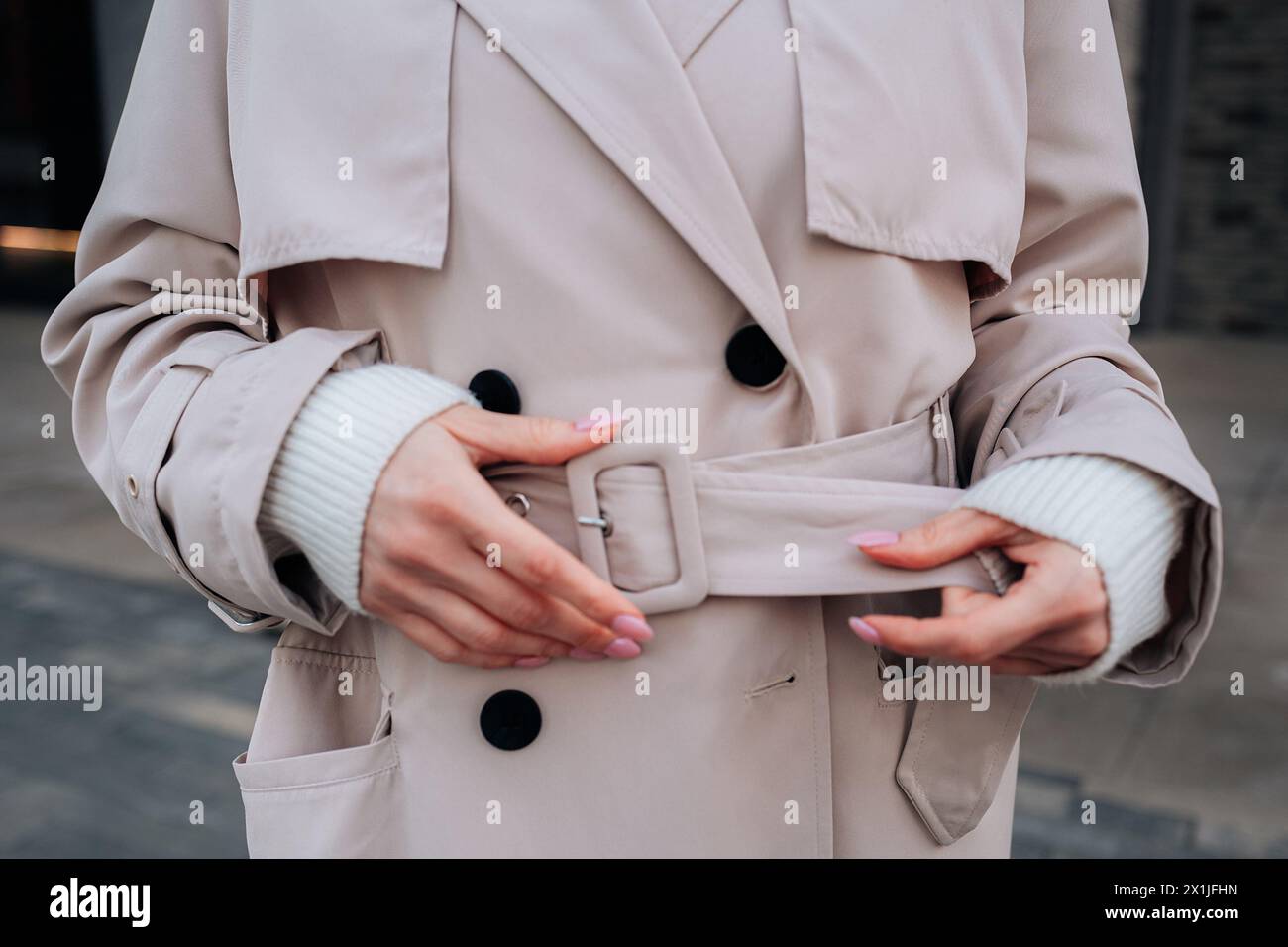 Street style fancy details of a beige women's trench coat with belt. Contemporary urban fashion cloth Stock Photo