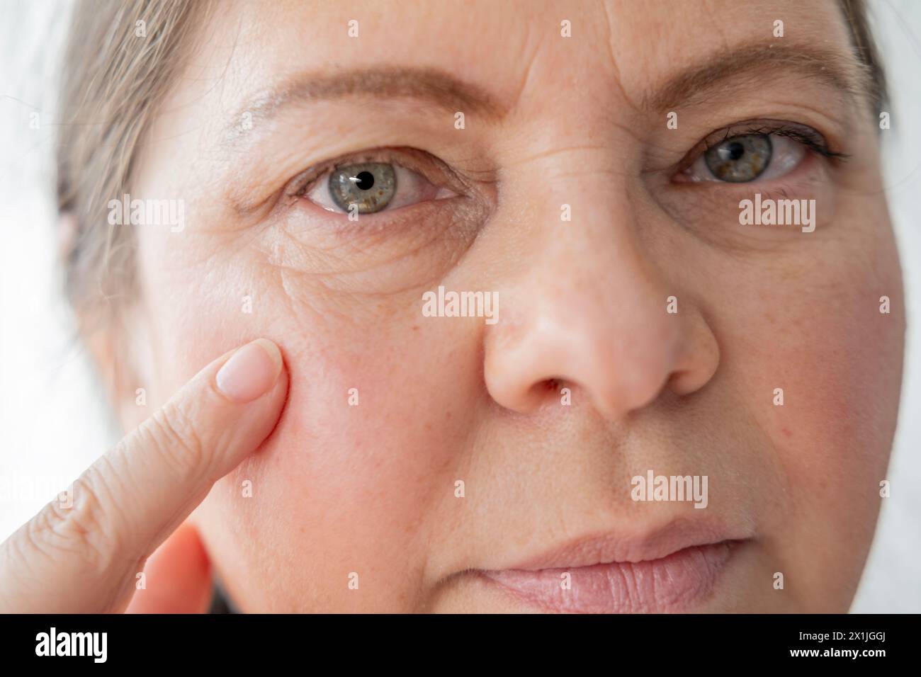 close up mature female face, aging woman 55 years old gazes herself in