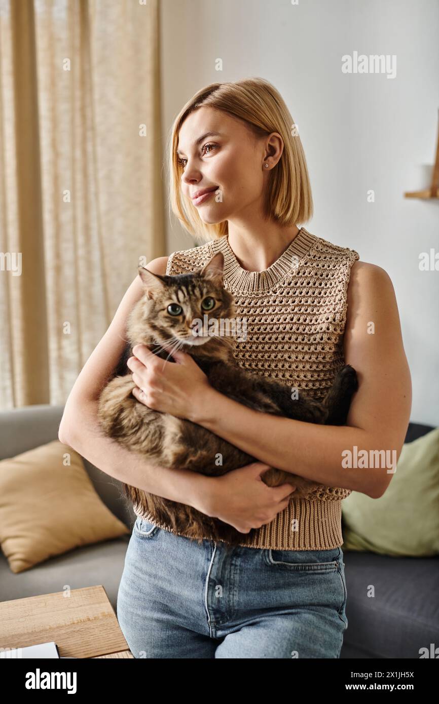 A woman with short hair tenderly cradling her cat in her arms, sharing a moment of quiet joy at home. Stock Photo