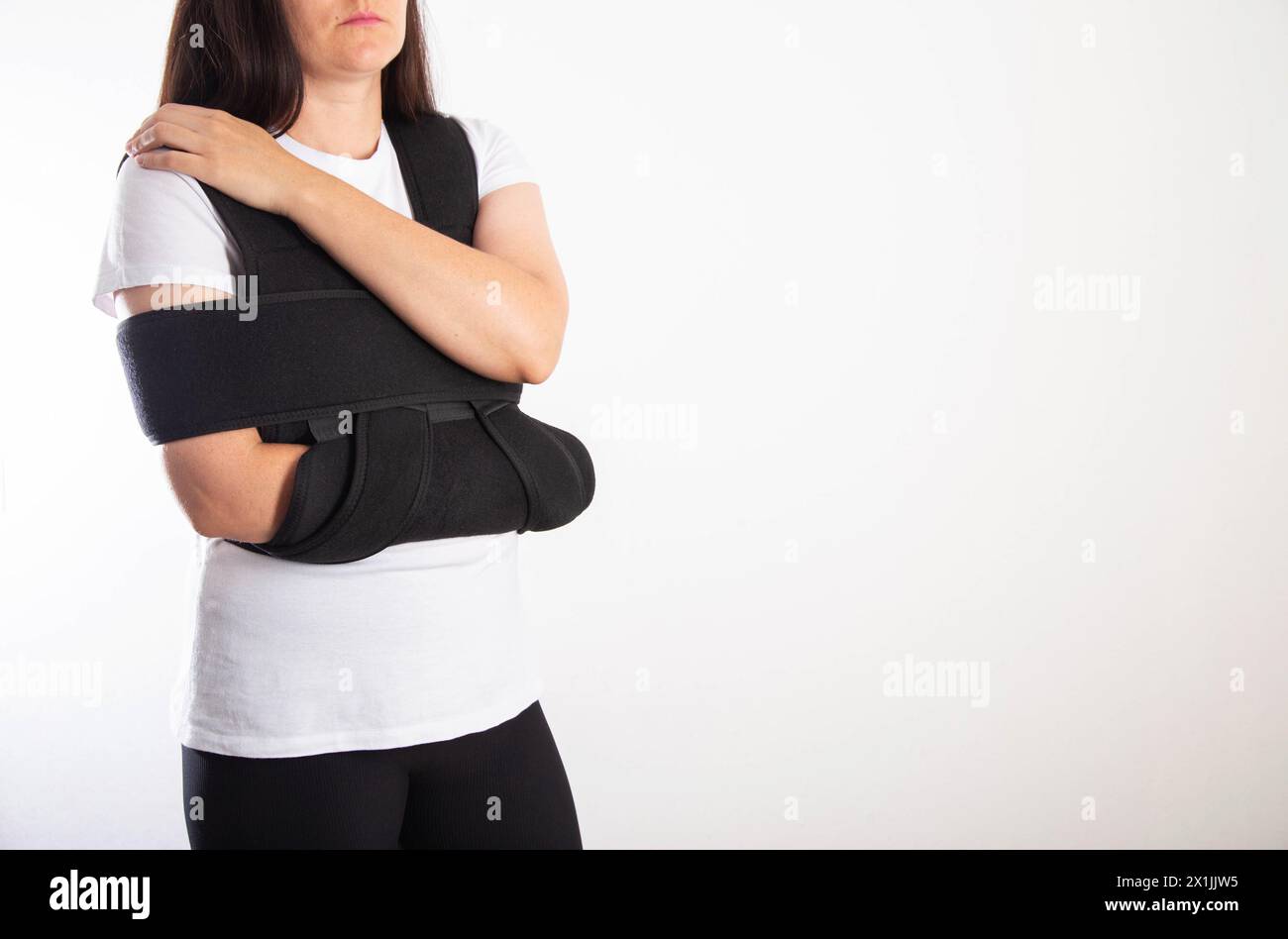 A girl in a black medical brace on the shoulder joint for rehabilitation after a fracture of the humerus and dislocation. Post-traumatic immobilizatio Stock Photo
