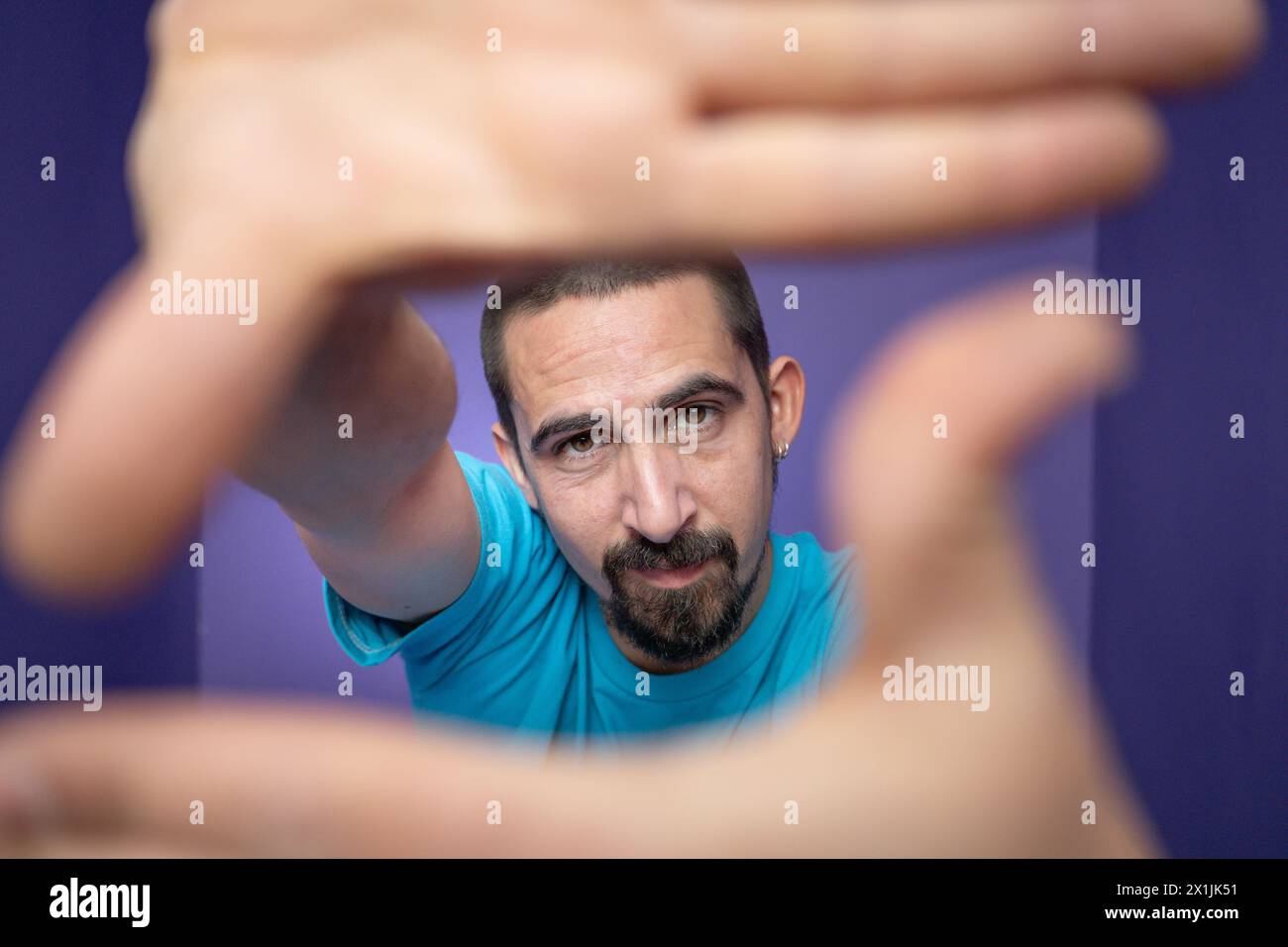 Young man doing frame using hands and fingers, isolated over purple background Stock Photo