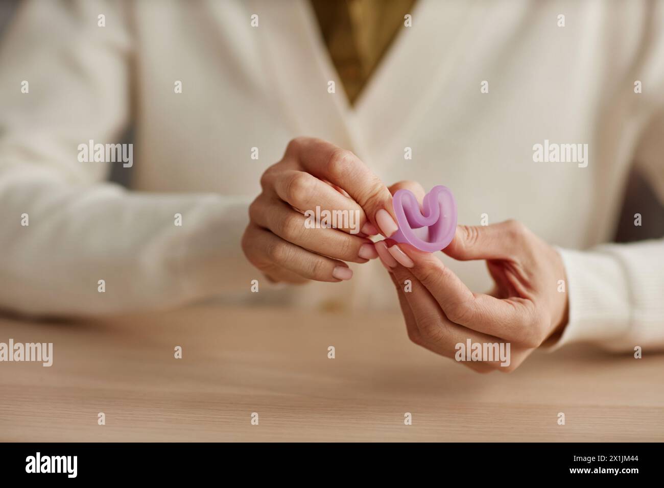 Close up of woman holding pink menstrual cup and demonstrating proper folding technique copy