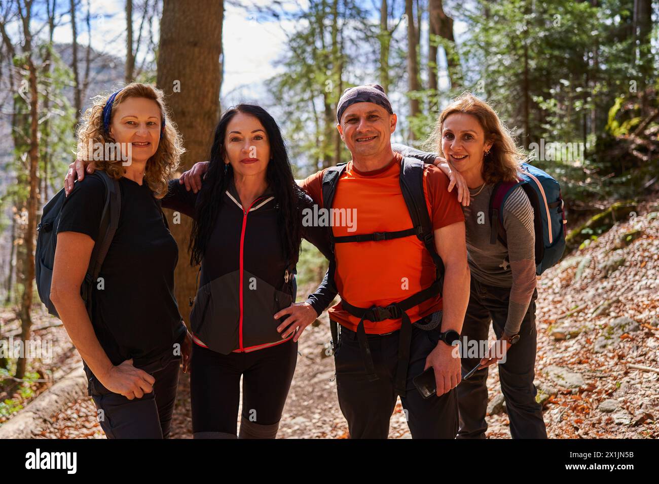 Mixed group of hikers with a man and three women with backpacks on a trail in the highlands Stock Photo
