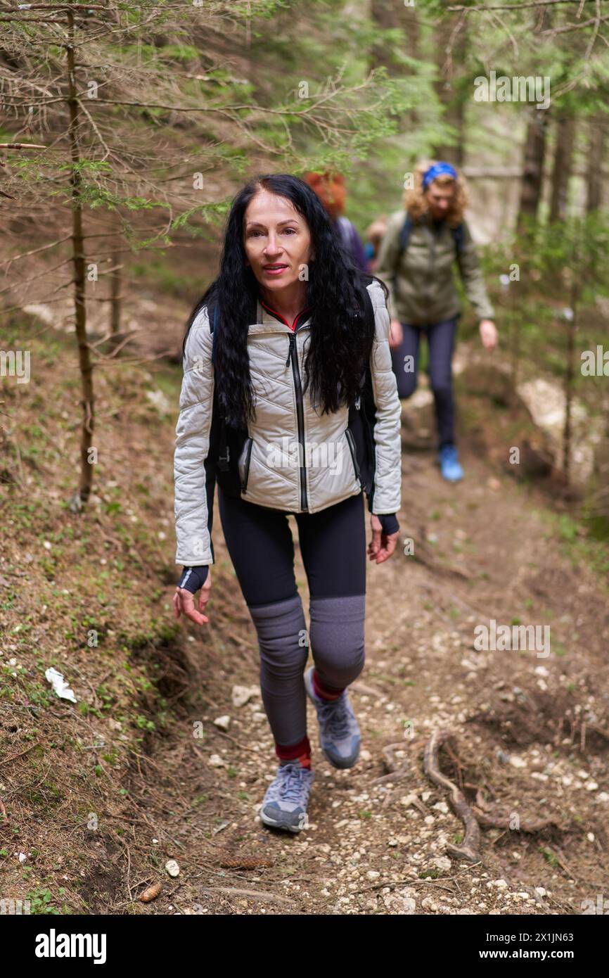 Group of women hikers with backpacks hiking on a trail in the mountains Stock Photo