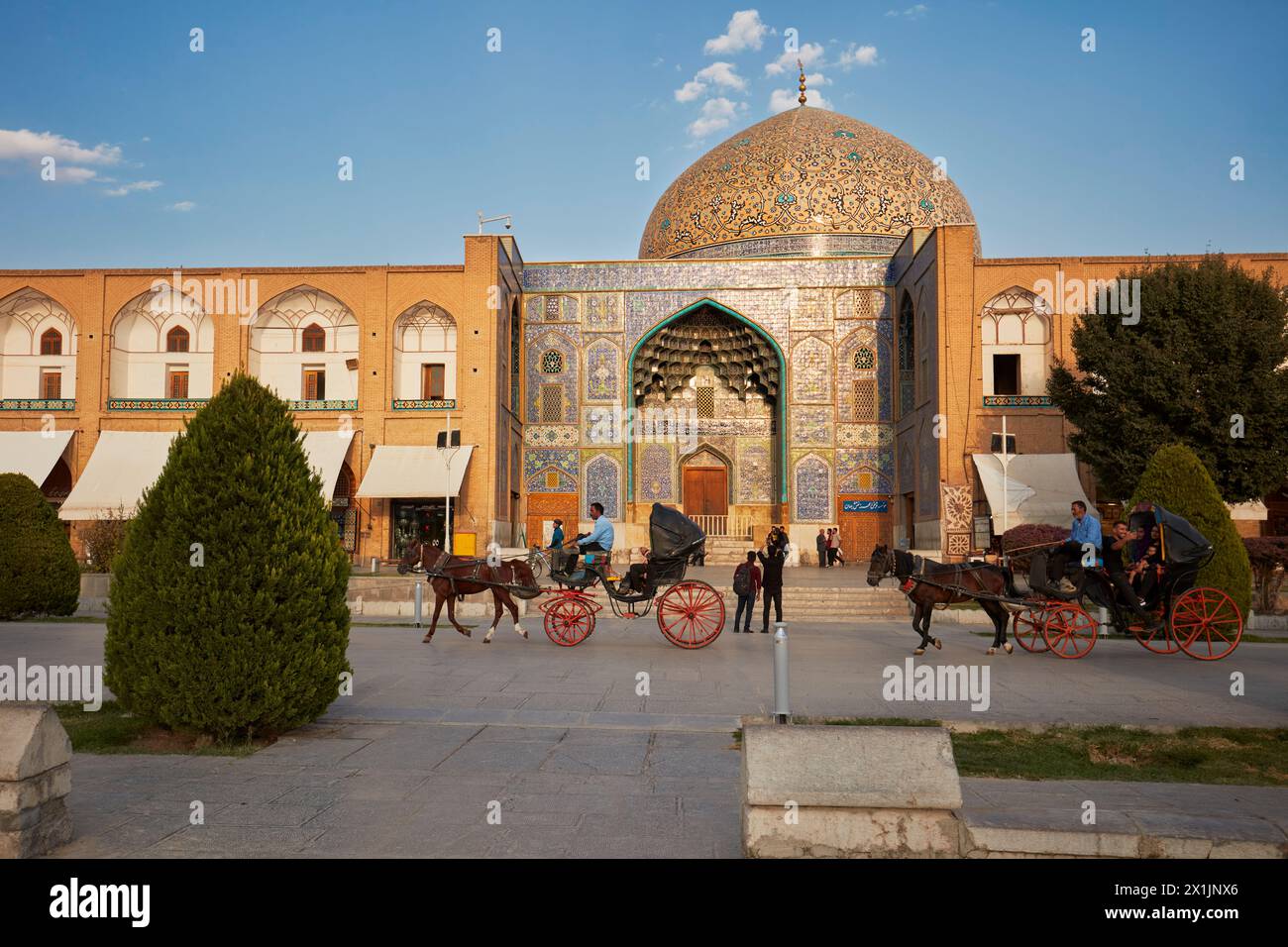 Horse drawn carriagees pass in front of the Lotfollah Mosque in Naqsh-e Jahan Square. Isfahan, Iran. Stock Photo