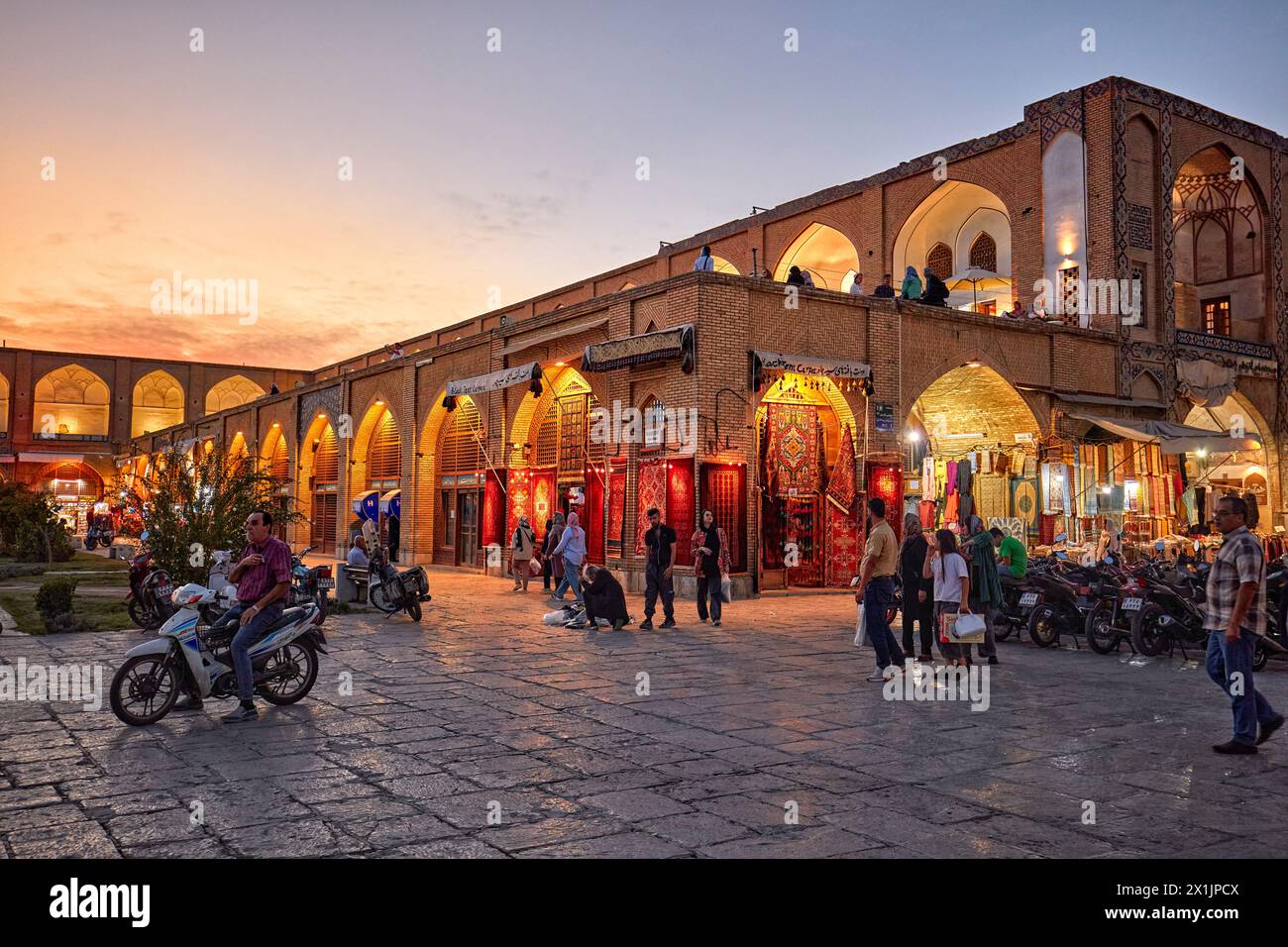 People walk in Naqsh-e Jahan Square illuminated at dusk. Isfahan, Iran. Stock Photo