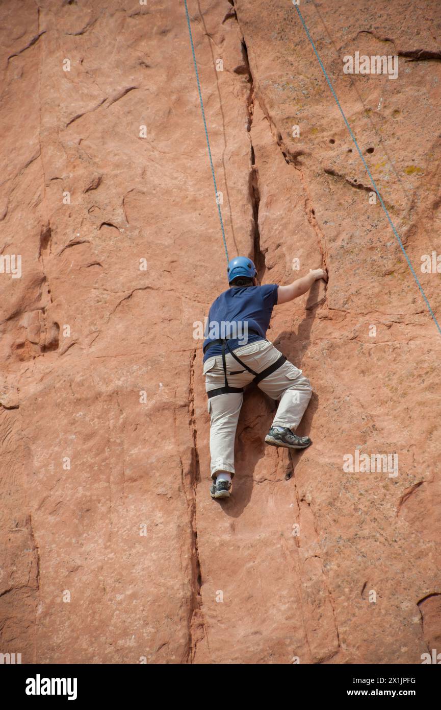 An adventurous climber ascends a sheer rock face, reflecting the challenge and thrill of sports in the beautiful mountains and nature of Colorado's he Stock Photo