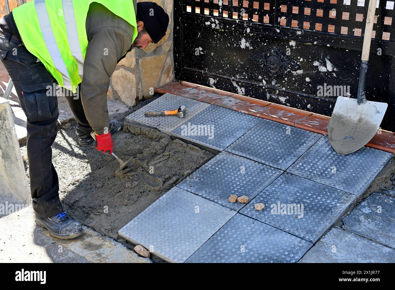 Workman laying standard paving slabs outside on a bed of cement Stock Photo
