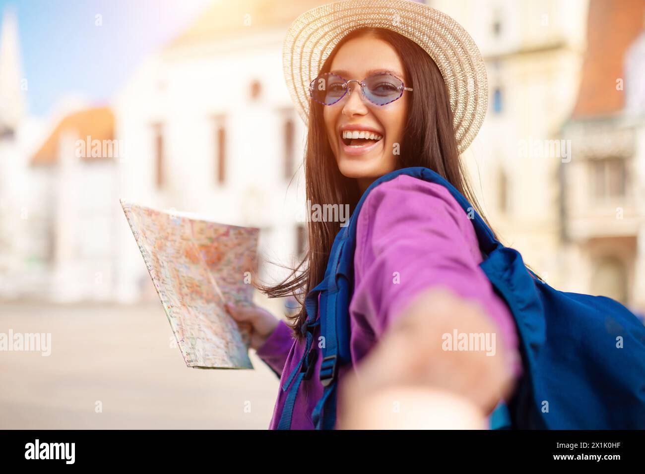 Excited woman using map and extending hand Stock Photo
