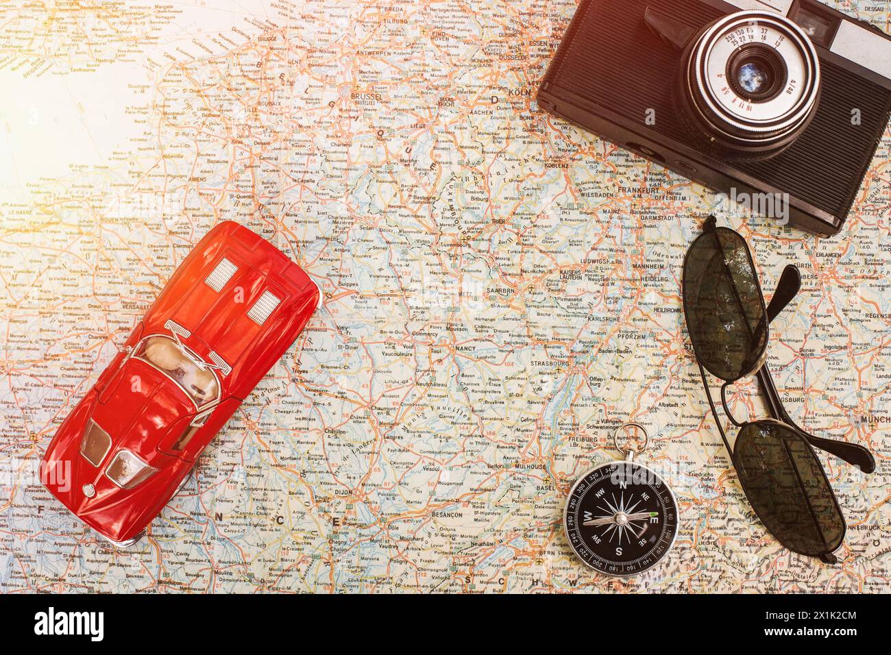 Traveling by car. Vintage red toy car, camera, compass and sunglasses lying on the map Stock Photo