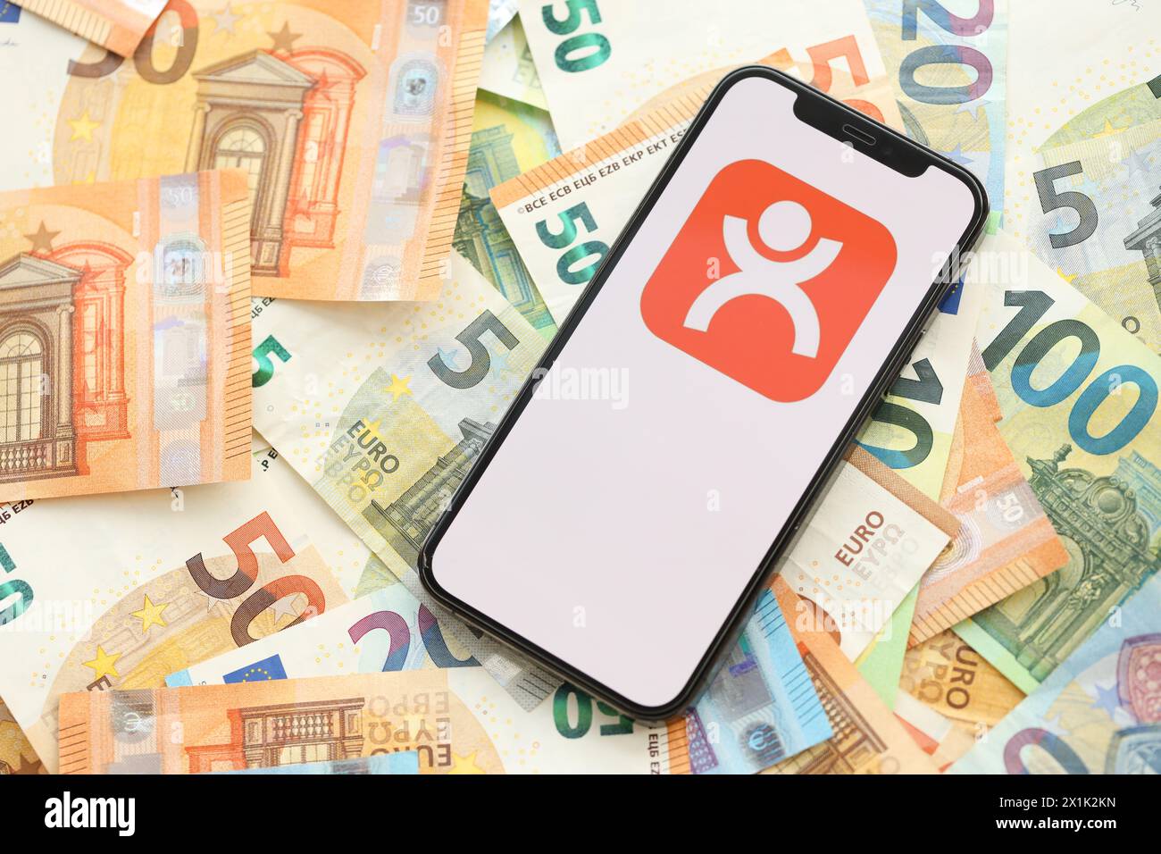 KYIV, UKRAINE - APRIL 1, 2024 Dianping platform icon on smartphone screen on many euro money bills. iPhone display with app logo with european currency euro banknotes Stock Photo