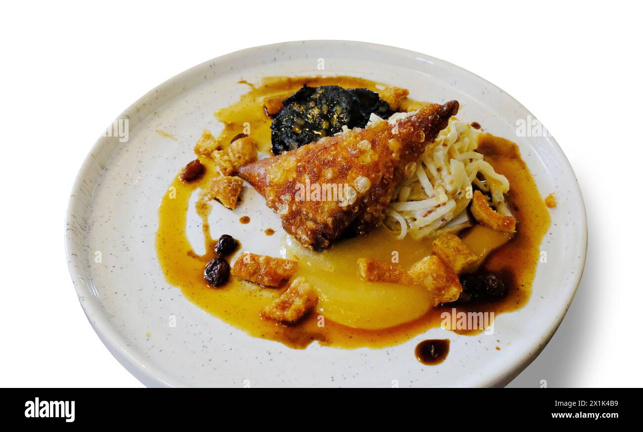 Studio shot of crispy pork belly, black pudding and apple sauce cut out against a white background - John Gollop Stock Photo