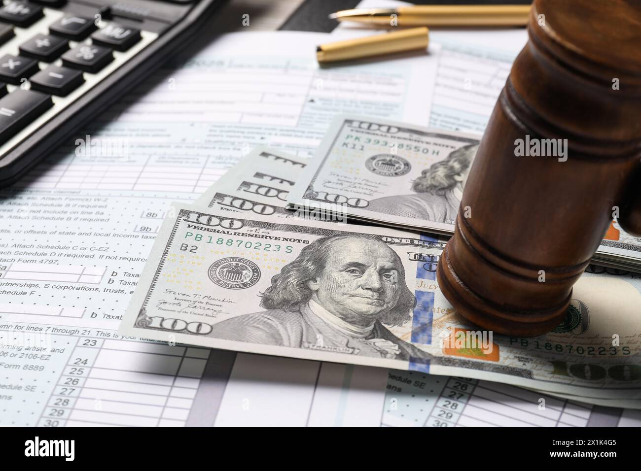 Tax return forms, dollar banknotes, gavel and calculator on table, closeup Stock Photo