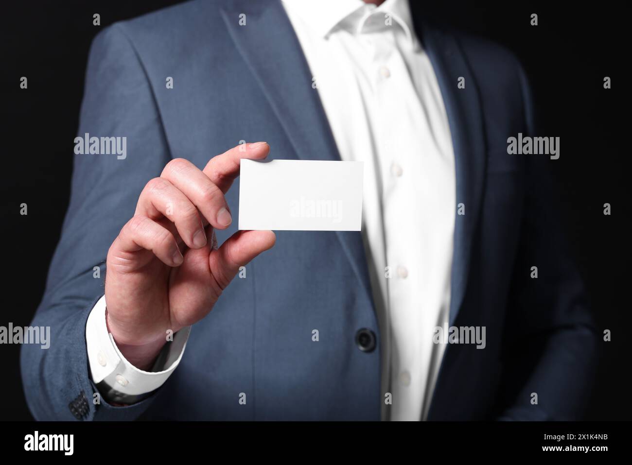 Businessman holding blank business card on black background, closeup Stock Photo