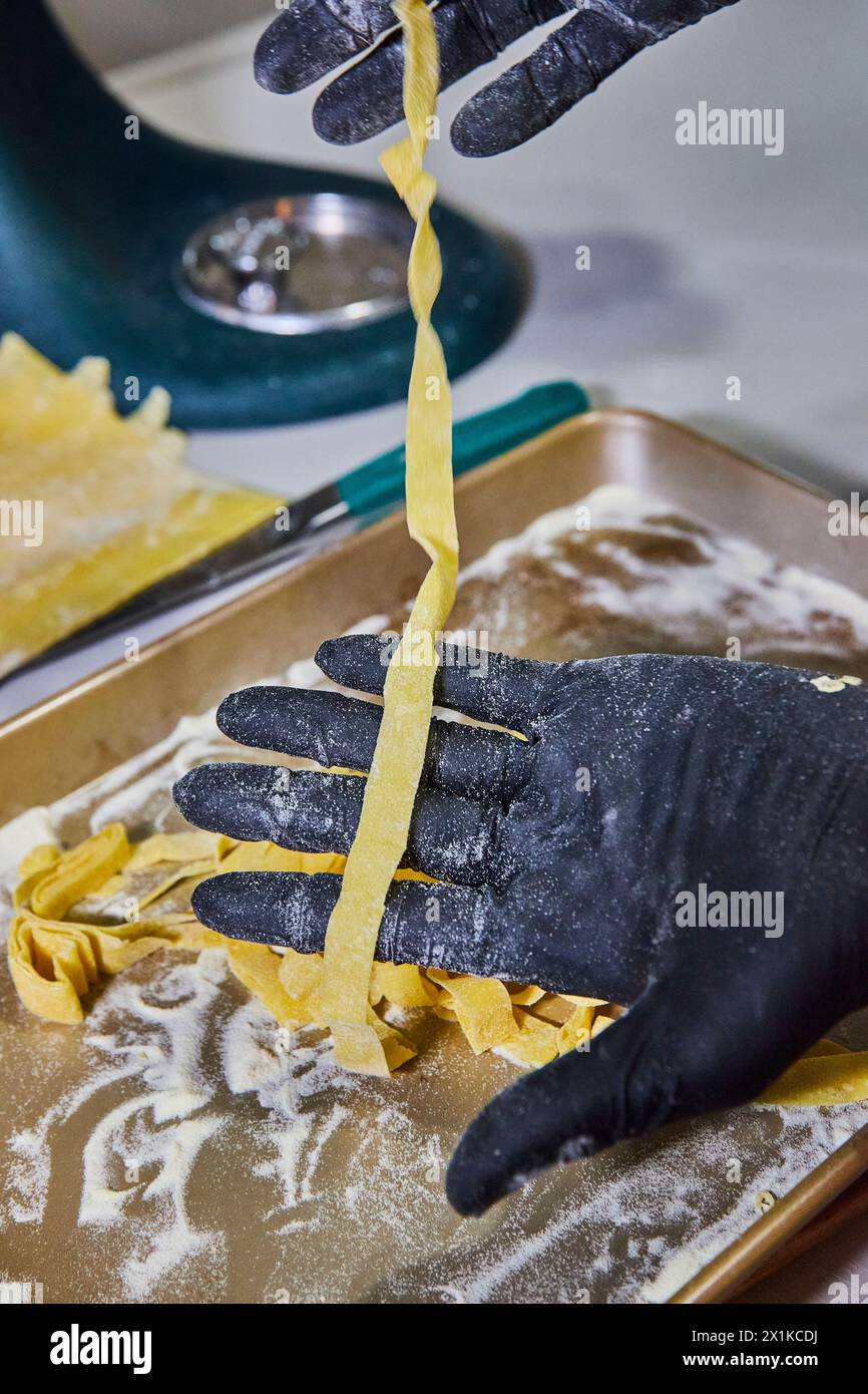 Fresh Fettuccine in Gloved Hand with Kitchen Backdrop Stock Photo