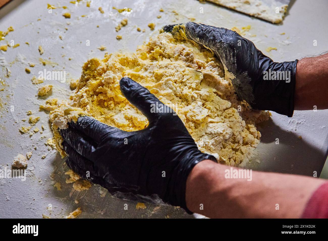 Artisan Kneading Dough with Black Gloves, Eye-Level Kitchen View Stock Photo