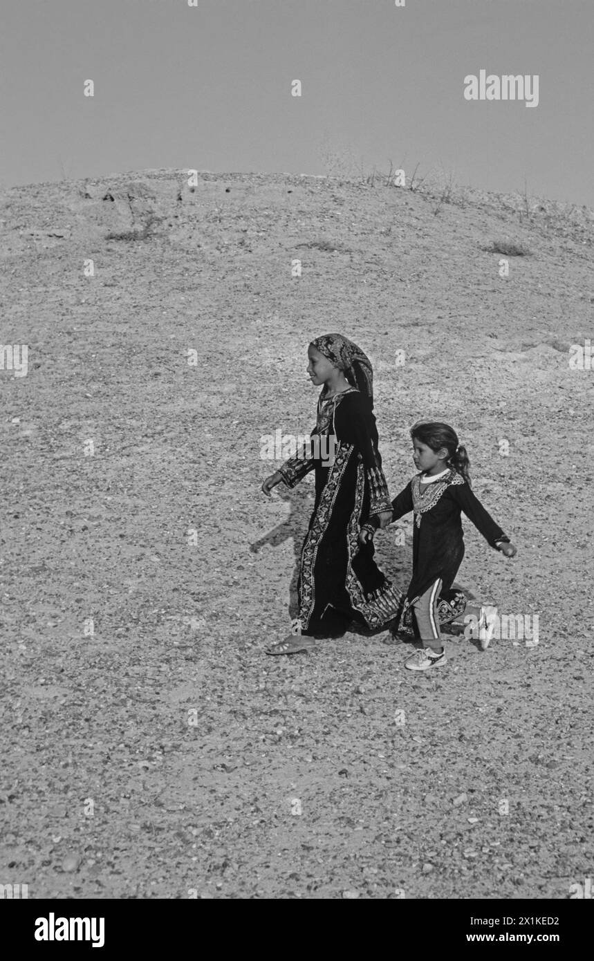 Bedouin girls walking in the desert Stock Photo