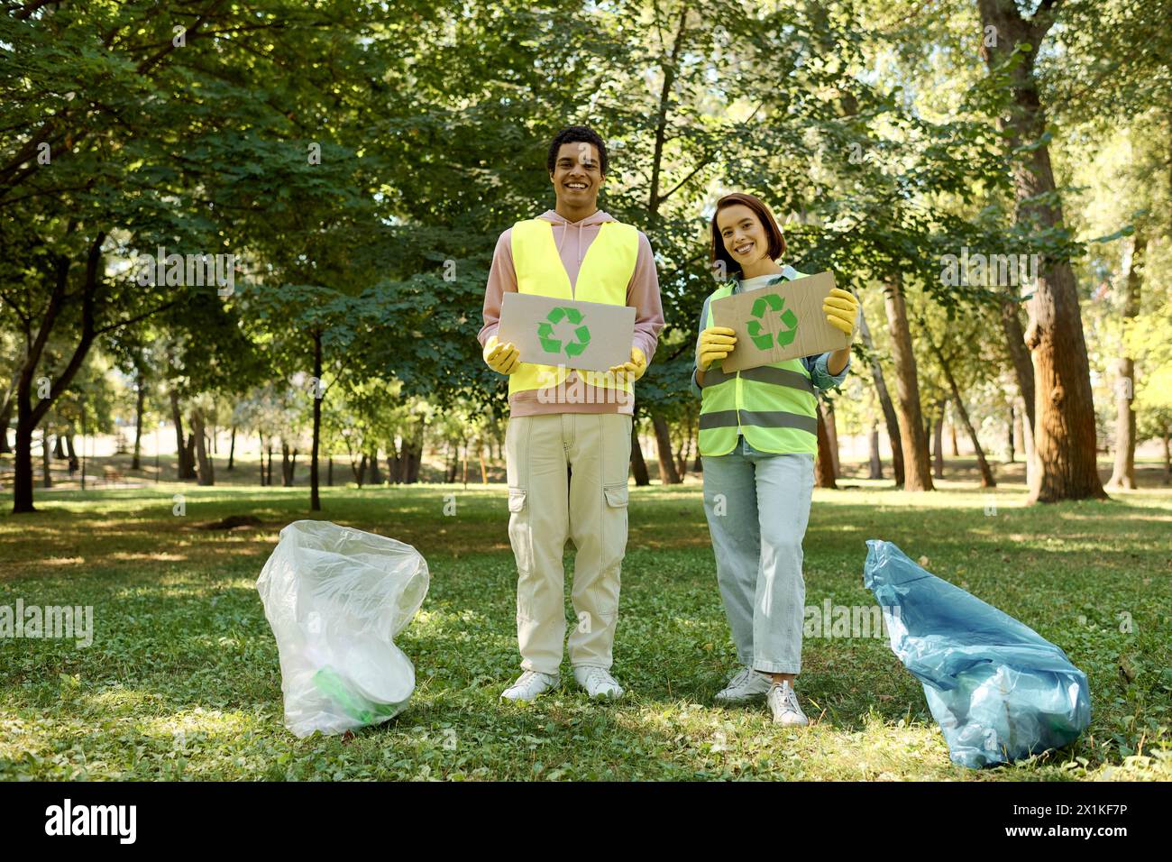 A diverse couple in safety vests and gloves holding up signs in a park
