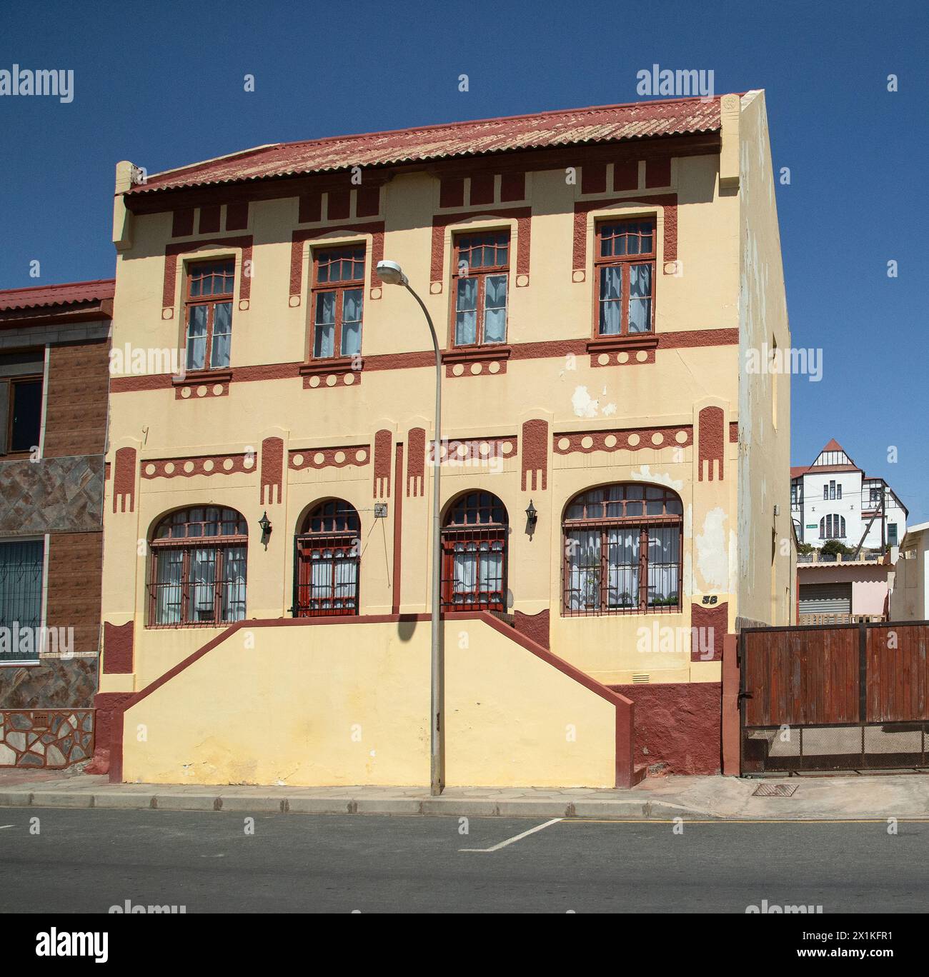 Historic, cream, German Colonial house with terracotta details and steps up to the door in Luderitz, Namibia. Stock Photo