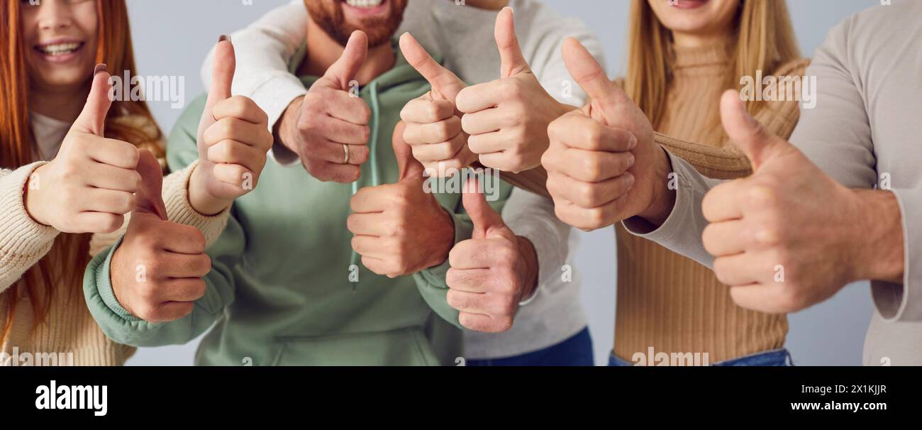 Happy smiling people friends putting their arms together in a line showing thumb up sign. Stock Photo