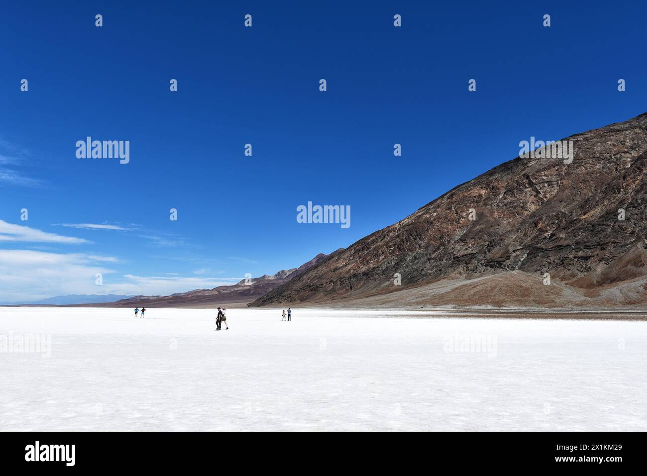 DEATH VALLEY NATIONAL PARK - 14 APR 2024: People walk onto the salt flat at Badwater Basin, the lowest point in North America. Stock Photo