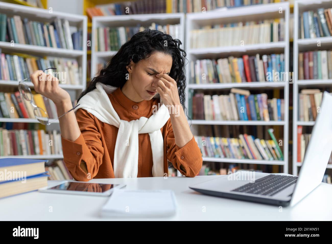 A Hispanic female student experiences stress and headache while working ...